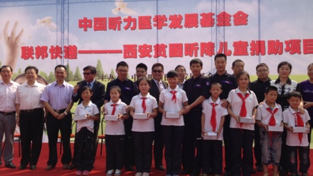1-联邦快递中国区总裁陈嘉良和联邦快递西安分公司员工志愿者一起给来自西安市第二聋哑学校的24名学生佩戴助听器.jpg